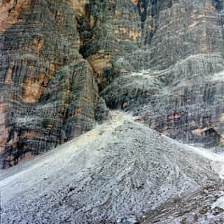 Pale scree slope spilling down beneath a towering striated cliff face