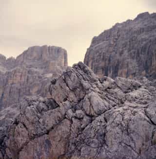 Rugged grey rock face and jagged mountain peaks under a hazy sky